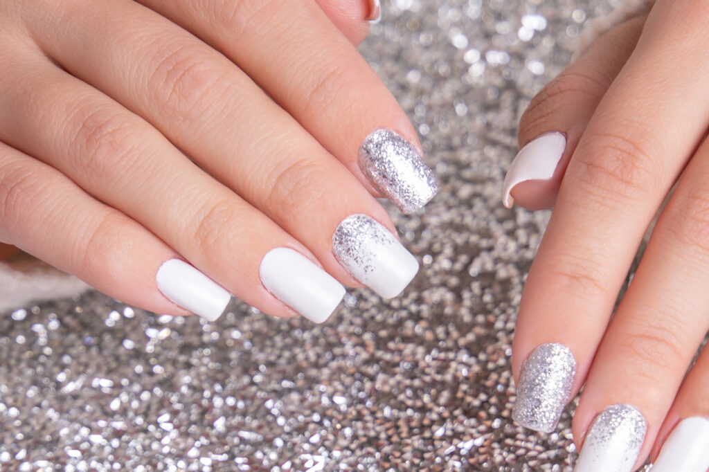 beautiful-female-hands-with-romantic-manicure-nails-white-gel-polish-with-silver-glitter-scaled.jpg